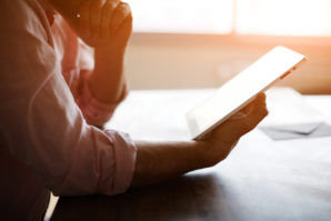 Male person looking to the digital tablet screen while sitting